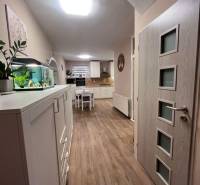 Innenraum eines Einfamilienhauses mit Küche, weißen Möbeln und einem Boden in Holzoptik.