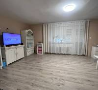 Ein Zimmer in einem Einfamilienhaus mit Holzboden, Fernseher und Vorhängen.
