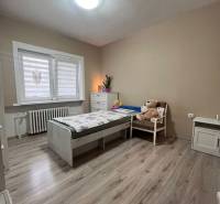 Kinderzimmer in einem Einfamilienhaus mit Bett, Stuhl und Boden in Holzoptik.