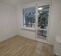 Ein Zimmer mit hellen Wänden, einem Boden in Holzoptik und Blick ins Grüne.