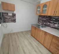 Die Küche in der 3-Zimmer-Wohnung hat einen Holzboden und einfache Schränke.