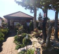 Ein Einfamilienhaus in Šaľa mit einem schönen Garten, Skulpturen und Bäumen im Hintergrund.