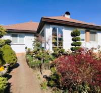 Ein Einfamilienhaus in Šaľa mit gepflegtem Garten, Gehweg und Grünflächen unter blauem Himmel.