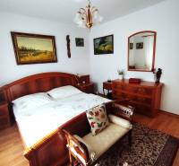 Ein Schlafzimmer in einem Einfamilienhaus mit Holzmöbeln, einem Boden mit Holzdekor und Bildern an der Wand.