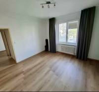 Ein Zimmer in einer 4-Zimmer-Wohnung mit einem Boden in Holzoptik, Vorhängen, Heizkörper.