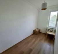 Ein Zimmer in einer 4-Zimmer-Wohnung mit einfacher Möblierung und einem Boden in Holzoptik.