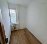 Ein kleiner Raum mit Holzboden in einer 4-Zimmer-Wohnung, Licht vom Fenster.