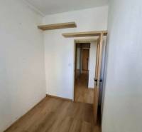 Ein Zimmer in einer 4-Zimmer-Wohnung mit einem Boden in Holzoptik und Regalen an der Wand.