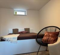 Schlafzimmer im Einfamilienhaus mit einem einfachen Bett und einem bequemen Sessel.