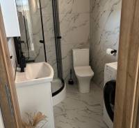 Badezimmer im Einfamilienhaus mit Marmorausstattung, Duschkabine und Waschmaschine.