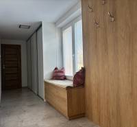 Flur in einem Einfamilienhaus mit Kleiderhaken und Sitzgelegenheit mit Kissen, Boden mit Holzdekor.