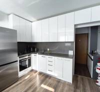 Küche mit weißen Schränken und Holzboden in einer Einzimmerwohnung.