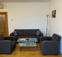 Graues Sofa in einer 3-Zimmer-Wohnung mit Holzboden und Glastisch.