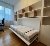 Ein Zimmer in einer 3-Zimmer-Wohnung mit einem Klappbett und einem Boden in Holzoptik.