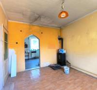 Ein Zimmer im Einfamilienhaus mit Kachelofen und einer Tür zur Küche.