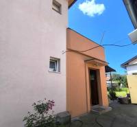 Ein Einfamilienhaus in Partizánske mit einem Hof, Blumen und einem Schlauch auf dem Betonweg.