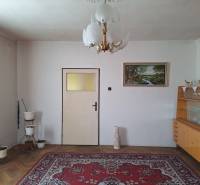 Wohnzimmer in einem Einfamilienhaus mit Teppich, Kronleuchter, Bild und Vitrine.