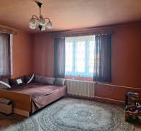 Ein Zimmer in einem Einfamilienhaus mit Bett, Teppich, Vorhängen und Nachttisch.