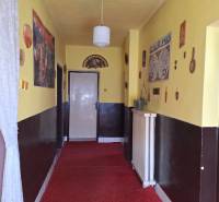 Ein Flur mit gelben Wänden, rotem Teppich und einer Hängelampe in einem Einfamilienhaus.