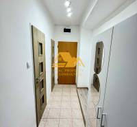 Ein Flur mit weißen Wänden, Fliesenboden und Holztüren in einer 3-Zimmer-Wohnung.