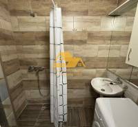 Badezimmer in einer 3-Zimmer-Wohnung mit Holzboden, Duschkabine und Waschmaschine.