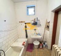 Badezimmer in einem Einfamilienhaus mit Badewanne, Waschbecken, Heizkörper und Fliesenboden.
