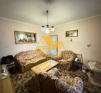 Wohnzimmer in einem Einfamilienhaus mit Sofa und Sesseln, dekoriert mit Bildern.