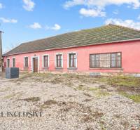 Ein Einfamilienhaus in Šintava mit steinernem Untergrund, rosa Fassade und Holzfenstern.