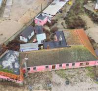 Ein Einfamilienhaus in Šintava mit einer älteren rosa Fassade, einem Betonhof und Anbauten.