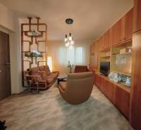 Wohnzimmer in einer 3-Zimmer-Wohnung mit braunem Sofa und Holzmöbeln.