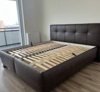 Schlafzimmer mit Bett ohne Matratze und Balkon in einer 2-Zimmer-Wohnung, Boden mit Holzdekor.