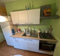 Küche in einer Einzimmerwohnung mit weißen Schränken und einem Boden in Holzoptik.