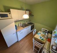 Eine Küche mit grünen Wänden, weißen Schränken und einem Holzboden in einer Einzimmerwohnung.