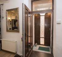 Eingangsflur mit Holztür, Spiegel und Vorhängen in einer 2-Zimmer-Wohnung.