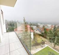 Balkon mit verglastem Geländer in einem Einfamilienhaus mit Blick auf die Umgebung.