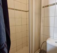 Badezimmer in einem Studio-Apartment mit Duschkabine und Toilette, gefliest mit weißen Fliesen.