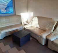 Beiges Sofa in der Hütte mit einem Rattantisch, Sonnenlicht durch das Fenster.