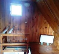 Innenraum der Hütte mit Holzboden und Treppe.