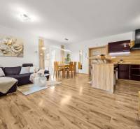 Wohnzimmer und Küche in einem Einfamilienhaus mit Holzboden, bequeme Couch.