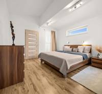 Schlafzimmer mit Holzboden, Bett und Kommode in einem Einfamilienhaus.