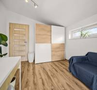 Ein Zimmer in einem Einfamilienhaus mit einem Boden in Holzoptik, einem Schrank und einem Sofa.