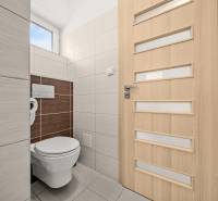 Toilette in einem Einfamilienhaus mit hellen Fliesen und Türen mit vertikalen Streifen.