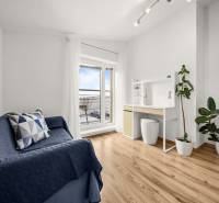 Ein Zimmer in einem Einfamilienhaus mit einem Holzboden, einem blauen Sofa und einem Schreibtisch.