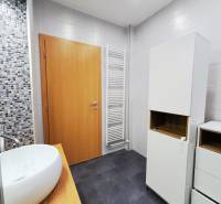 Badezimmer mit Waschbecken, weißen Schränken und Mosaikfliesen in einer 2-Zimmer-Wohnung.