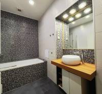 Badezimmer in einer 2-Zimmer-Wohnung mit Mosaikfliesen, Waschbecken und Badewanne.
