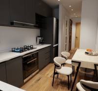 Küche einer 3-Zimmer-Wohnung mit Herd, Esstisch und Boden mit Holzdekor.