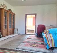 Ein Zimmer in einem Einfamilienhaus mit Bücherregalen, einem Bett mit einer bunten Decke und einem Teppich.