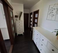 Flur in einer 3-Zimmer-Wohnung mit dunklem Boden und weißen Möbeln.