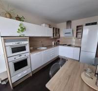 Küche in einer 3-Zimmer-Wohnung mit weißer Küchenzeile und Boden in Holzoptik.