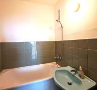 Badezimmer mit grünen Fliesen, Badewanne und Waschbecken in einer 4-Zimmer-Wohnung.